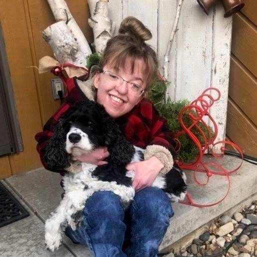 Resident holding a dog outdoors with festive decor.