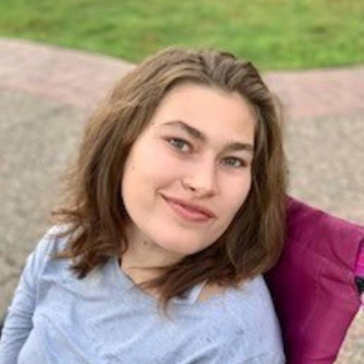 Young woman smiling outdoors in a wheelchair.