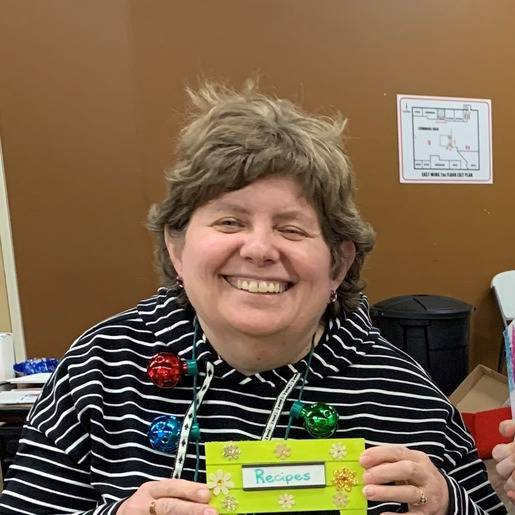 Resident holding a recipe card and smiling.