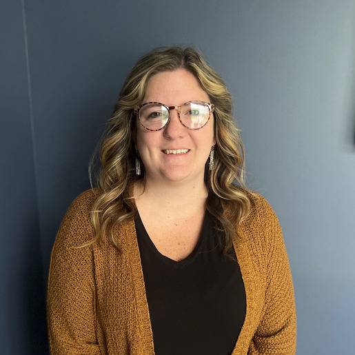 Staff member smiling against a blue wall.