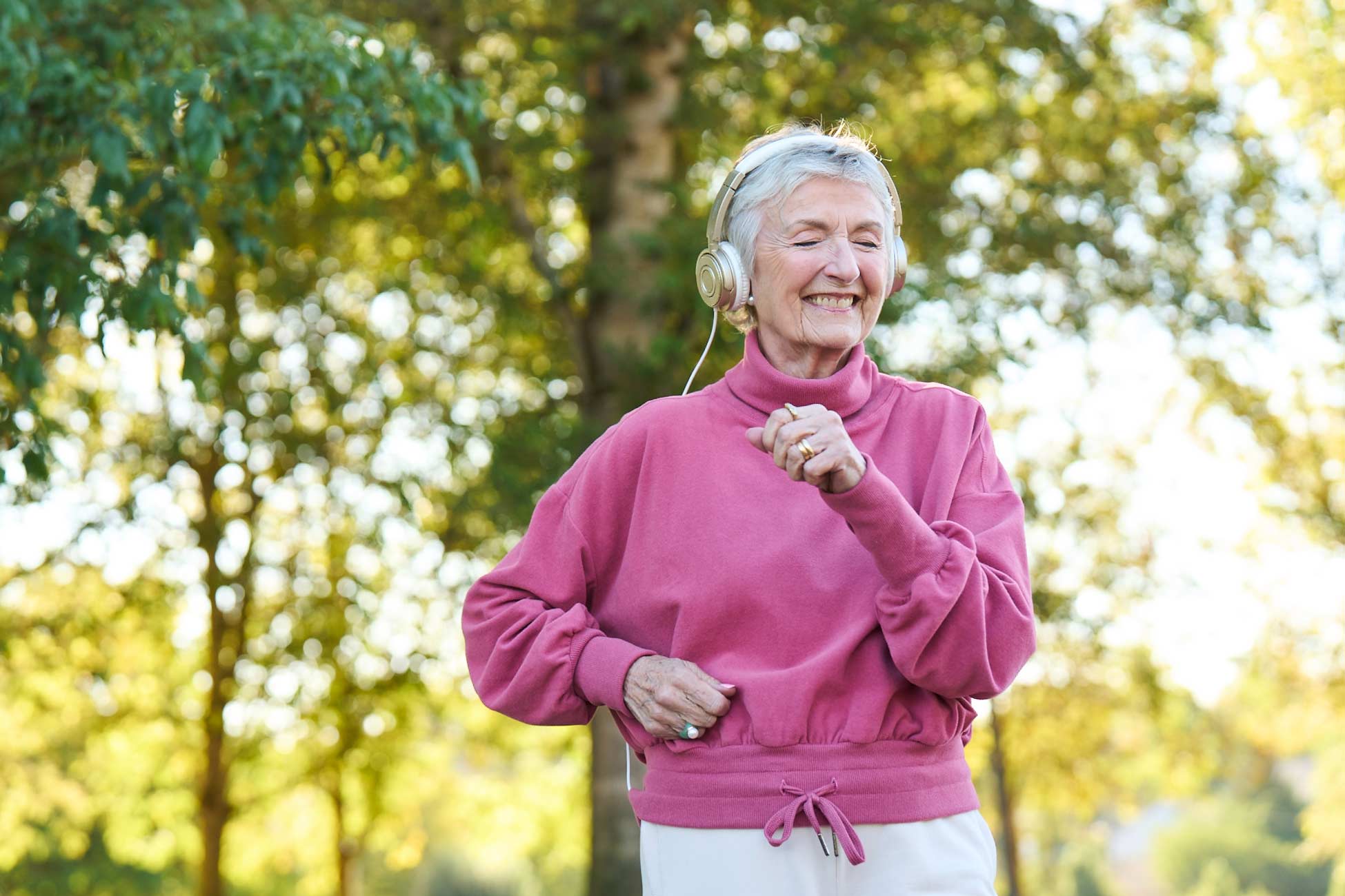 Senior woman enjoying music outside in a garden