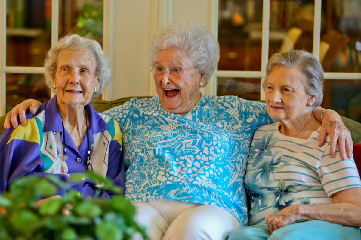 Three elderly women sitting together smiling