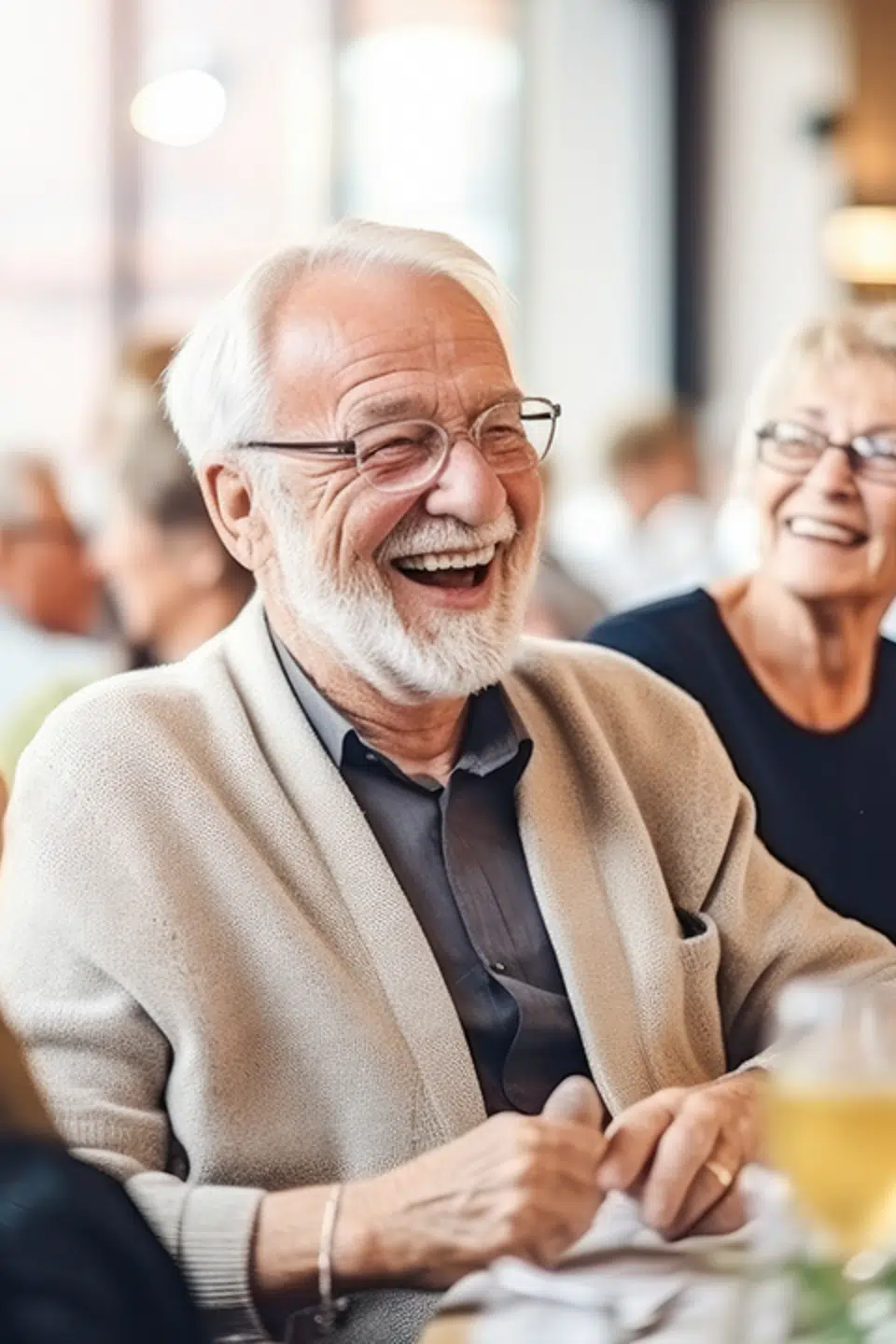 A senior man laughing with a group of people in a dining area