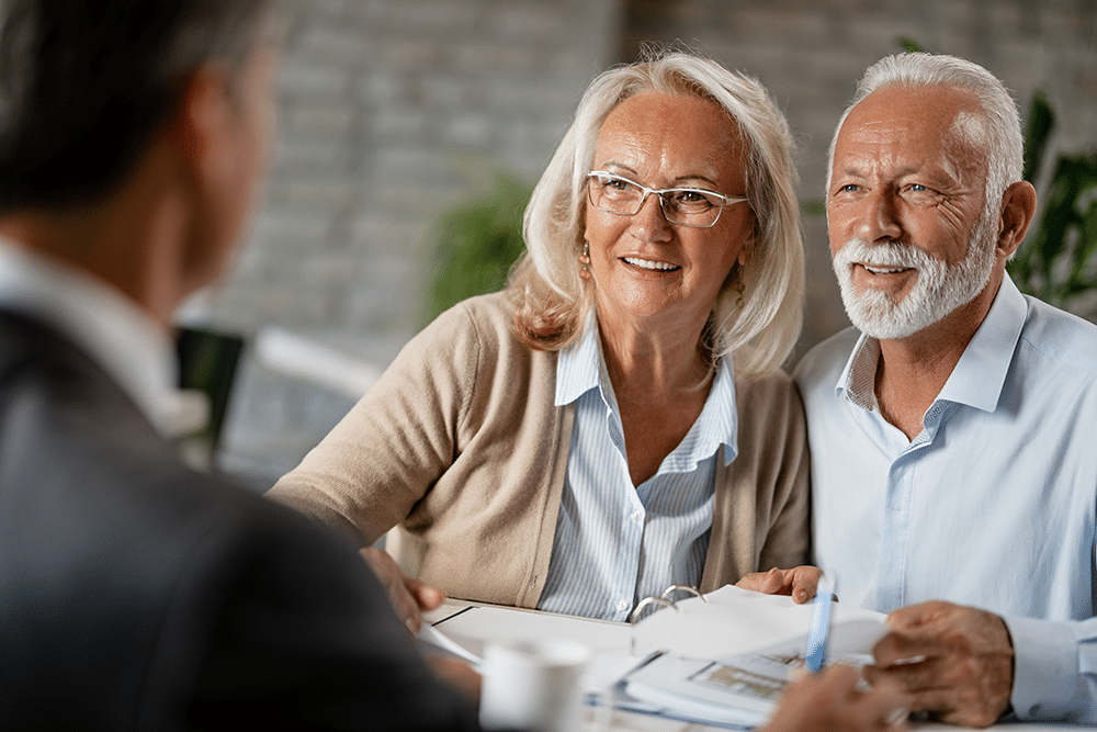 A senior couple smiling while engaging with a staff member