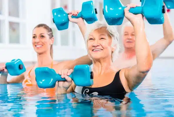 Seniors participating in water aerobics with weights