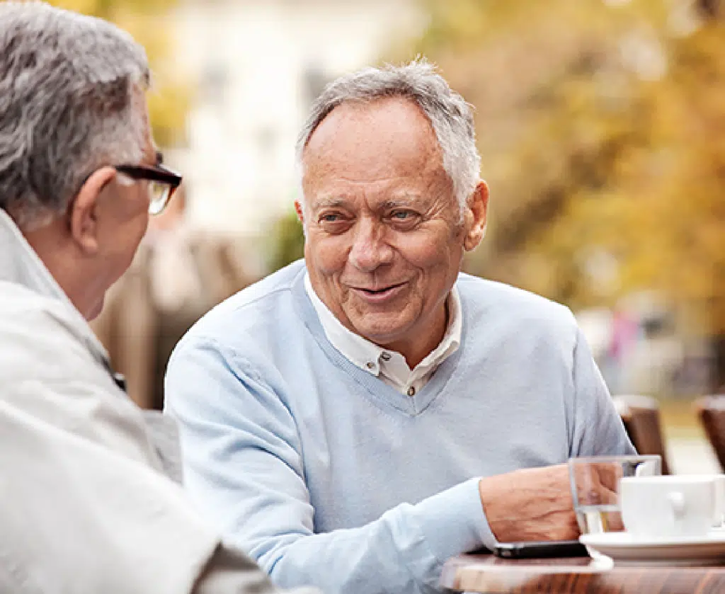 Two elderly men conversing outdoors in a relaxed setting