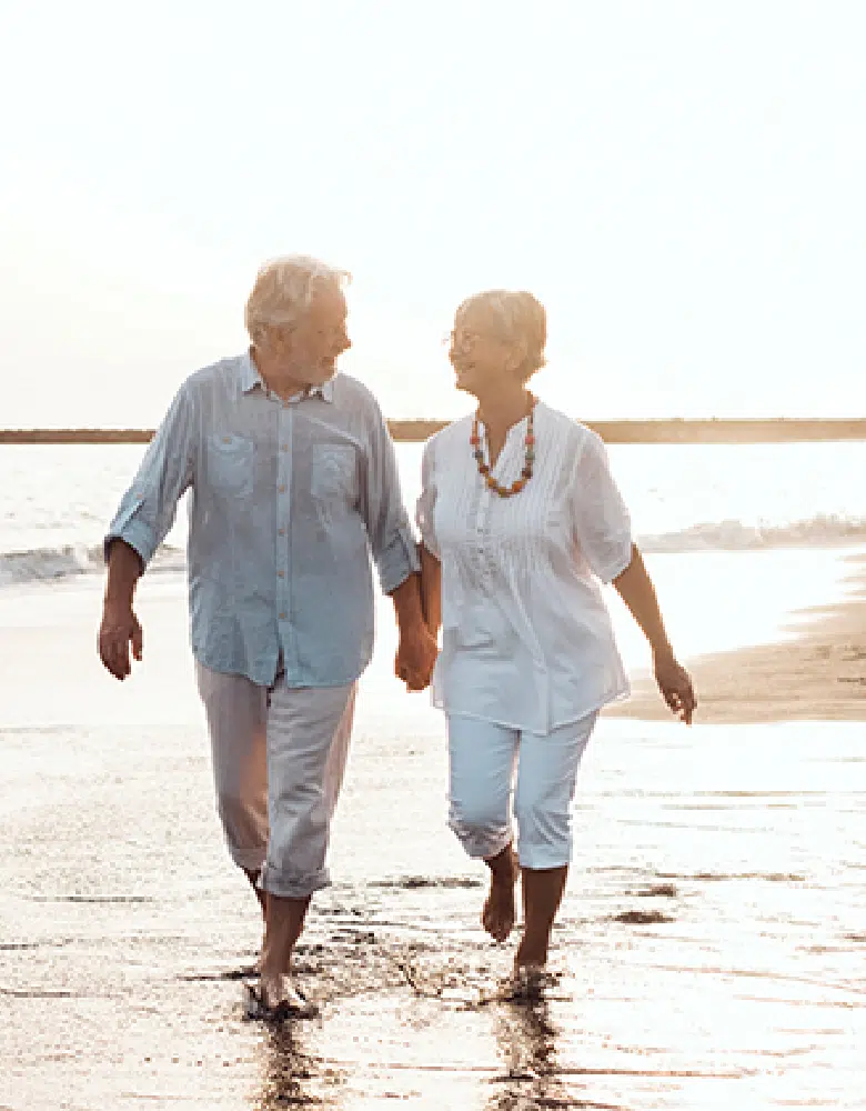 Couple walking hand in hand on the beach at sunset