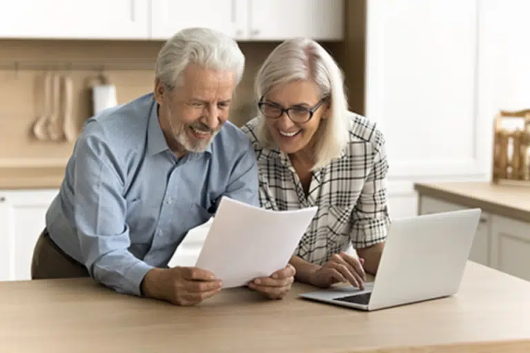 Two seniors smiling and reviewing documents together