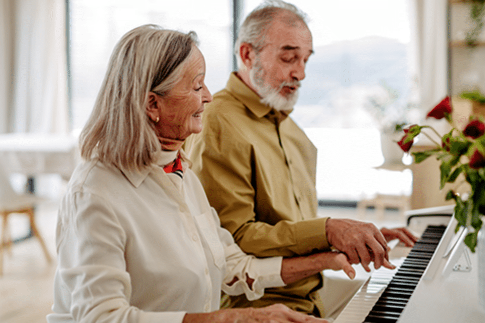 Residents playing piano together in a bright common area