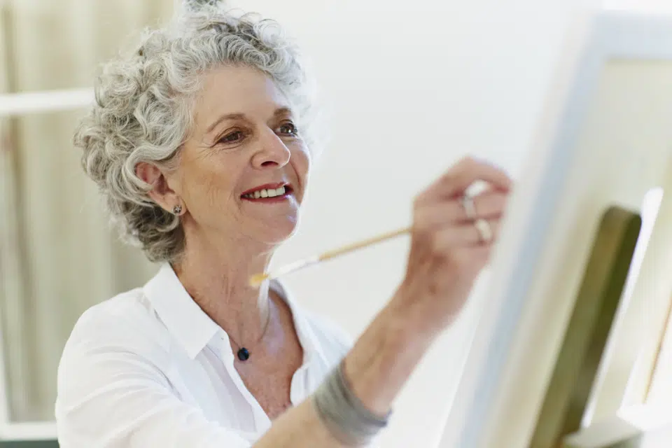 Senior woman enjoying painting in a bright room
