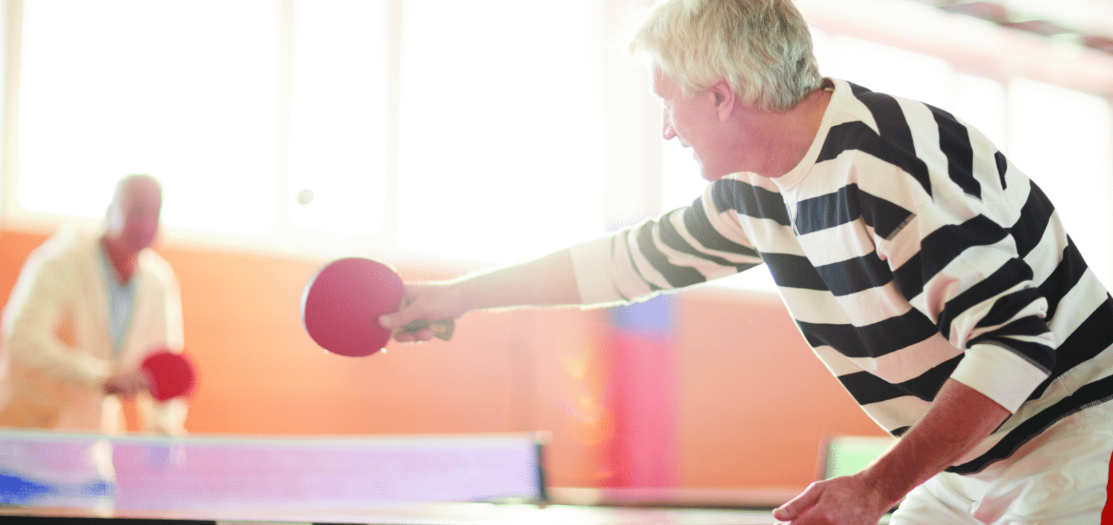 Residents playing table tennis in a bright activity room