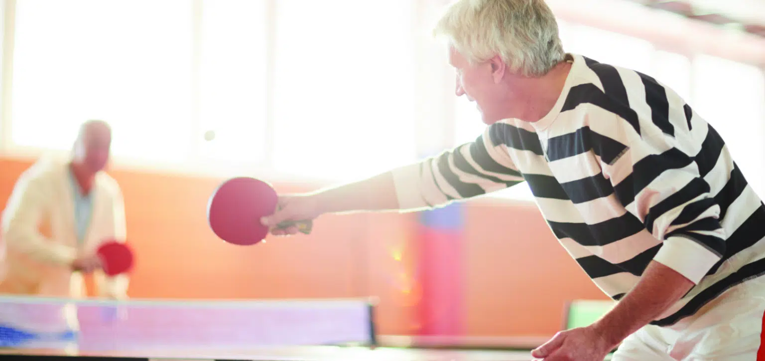 Residents playing table tennis in a bright activity room