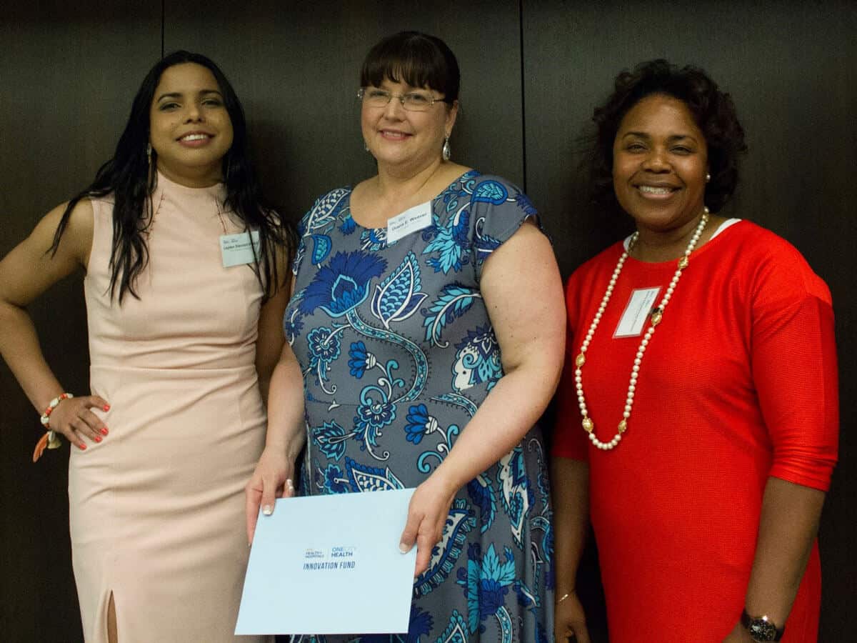 Three women smiling together at an event.