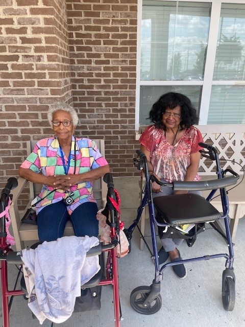 Two women sitting outside the facility in bright clothing