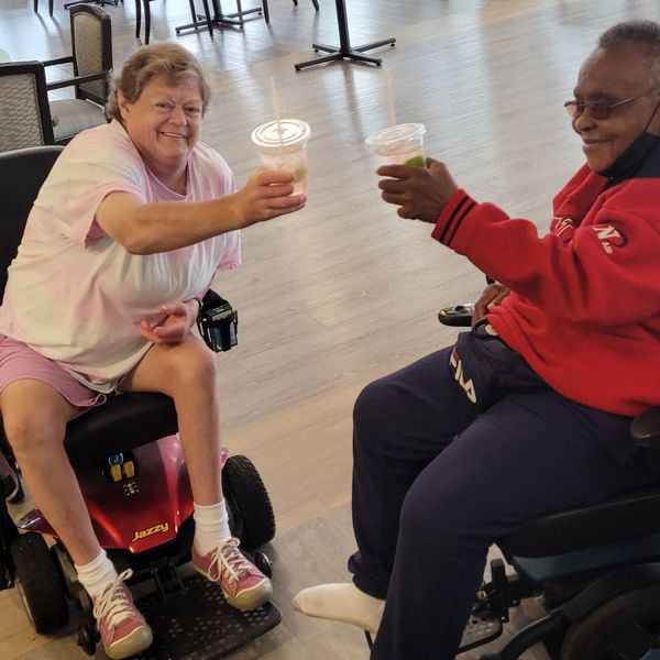 Two residents toasting with beverages in a common area