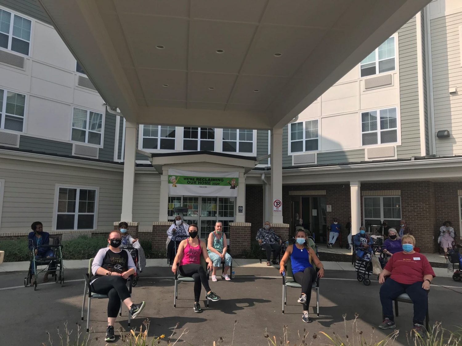 Residents participating in an outdoor activity in front of the facility