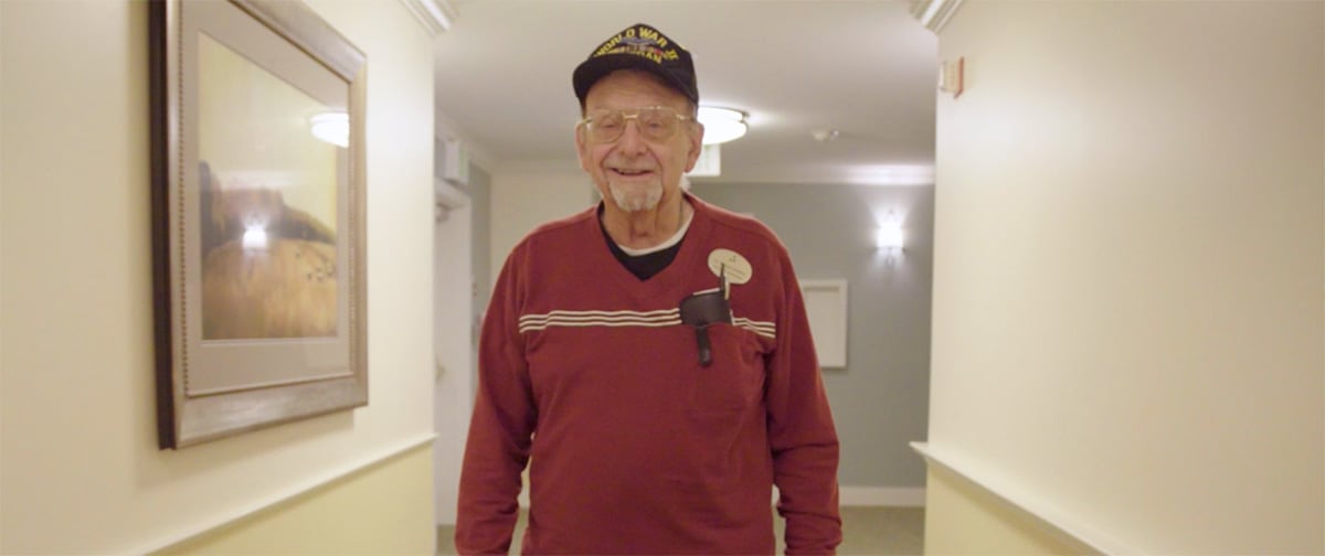 A smiling resident walking down a facility hallway