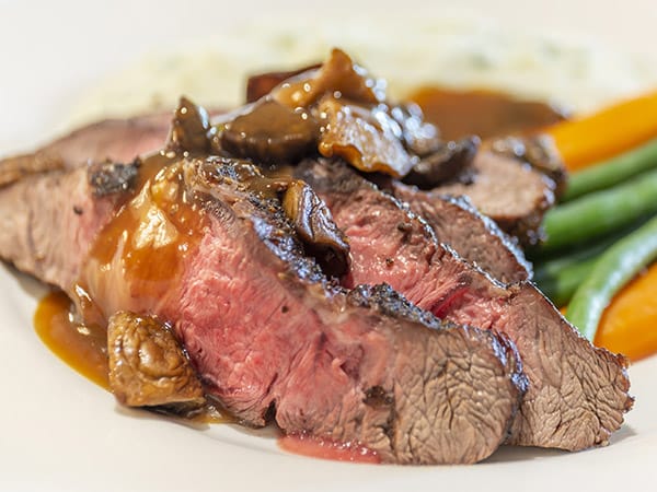 Close-up of a plated meal with beef, vegetables, and gravy