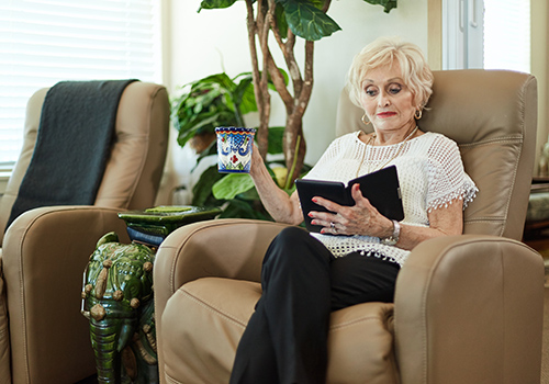 A senior woman reading a book in a comfortable chair