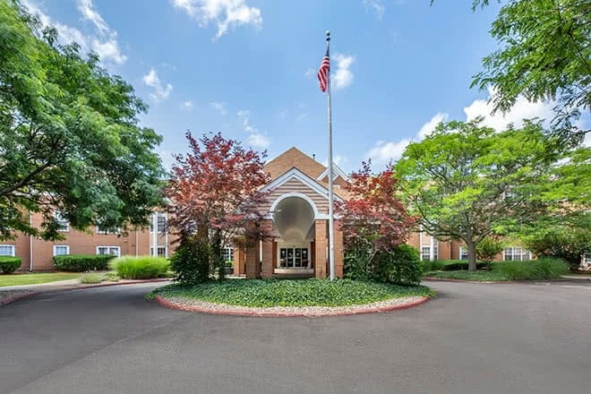 Entrance of a senior living facility surrounded by greenery