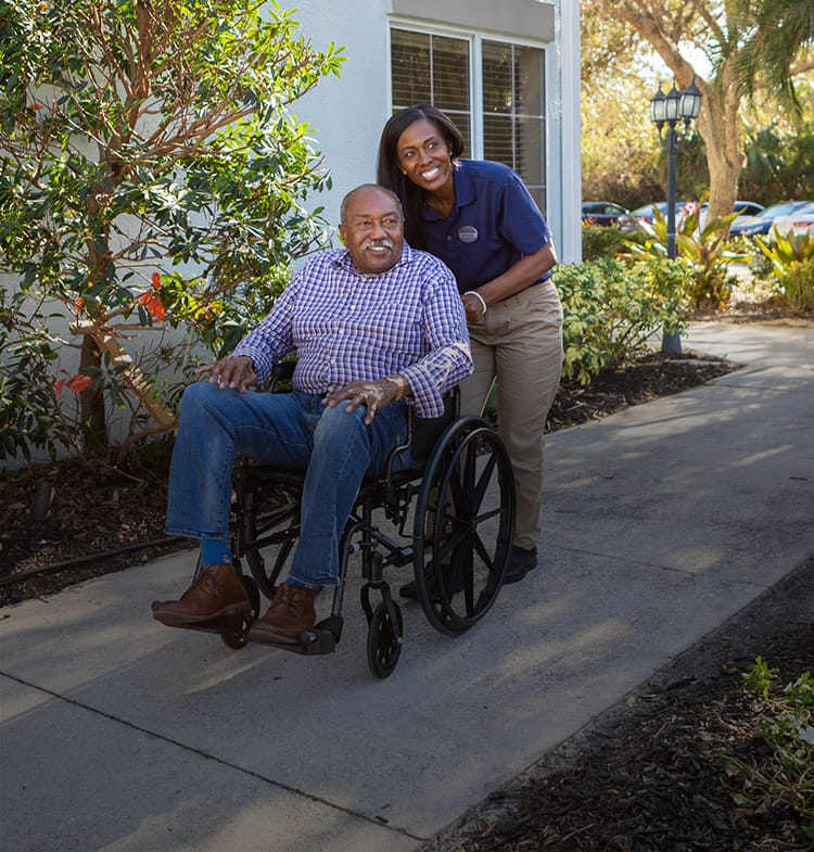 Resident in a wheelchair with a staff member outdoors