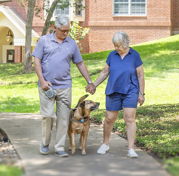 Residents walking a dog in a landscaped area