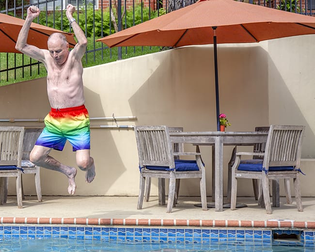 A resident jumping into a pool during a summer activity