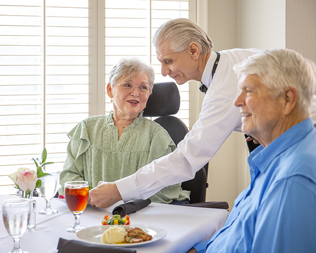 Dining room scene with residents and a waiter