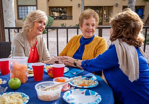 Three women enjoying a meal outdoors at a table