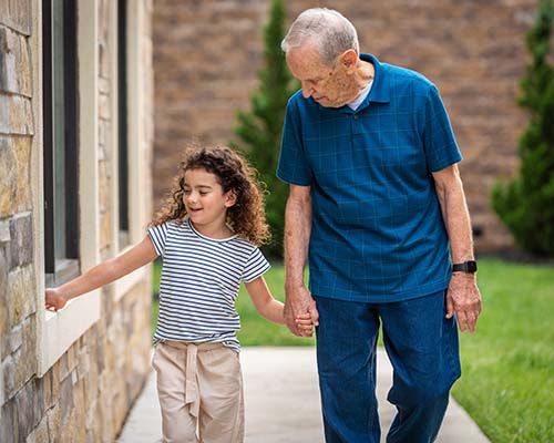 Elderly man walking with young girl outdoors