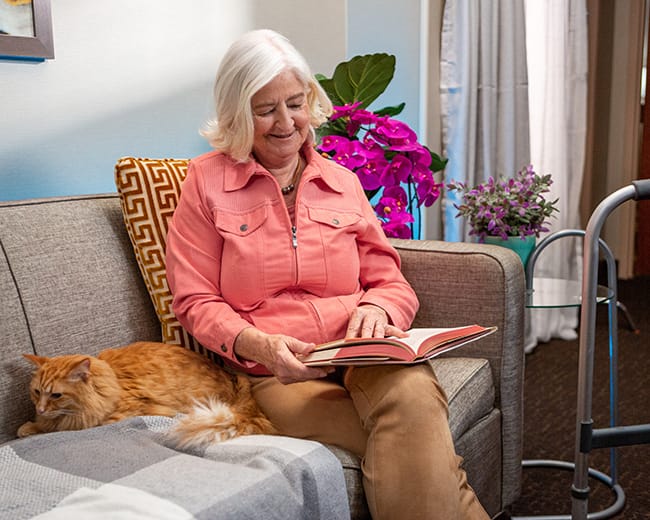 Resident reading in a cozy living area with a cat