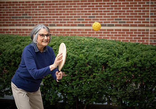 Resident playing pickleball outside