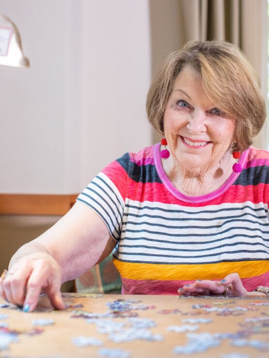 Resident enjoying a puzzle in a bright activity area