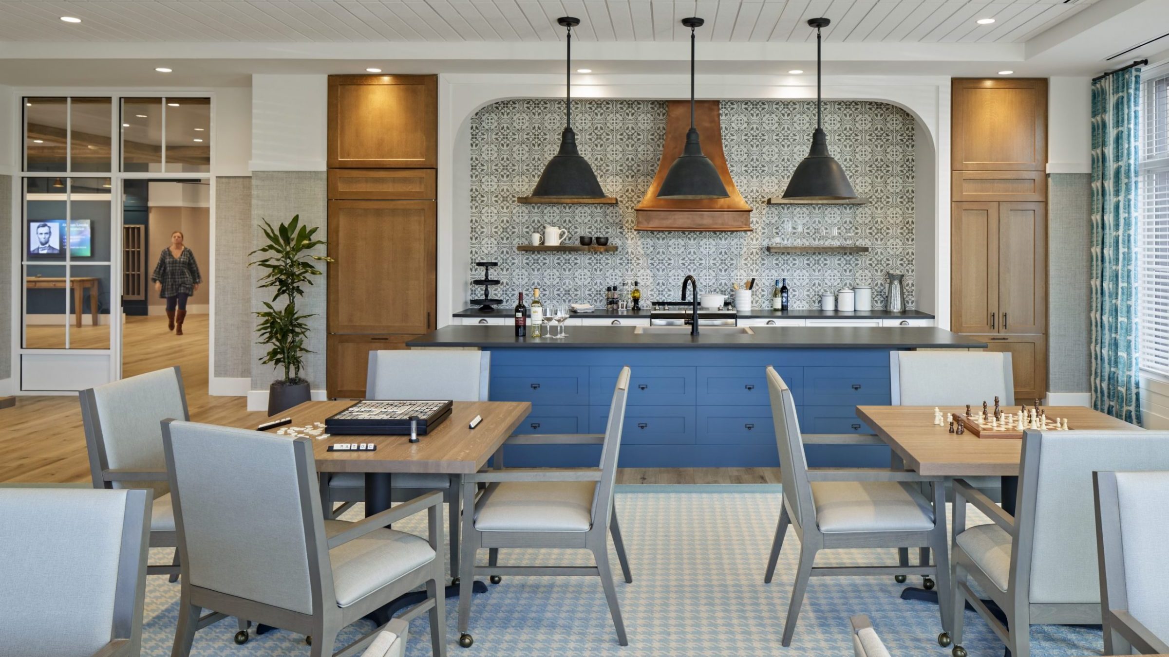 Bright common area with tables and chairs, and residents visible