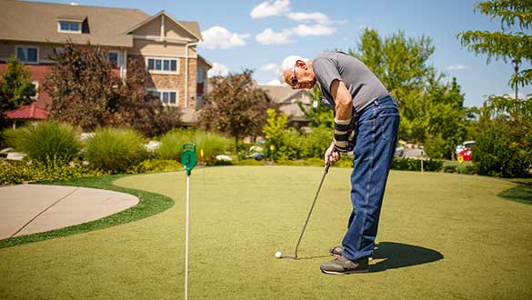 Resident putting on the mini-golf green outside