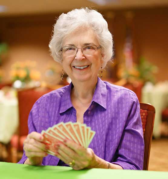 Senior woman playing cards in a common area