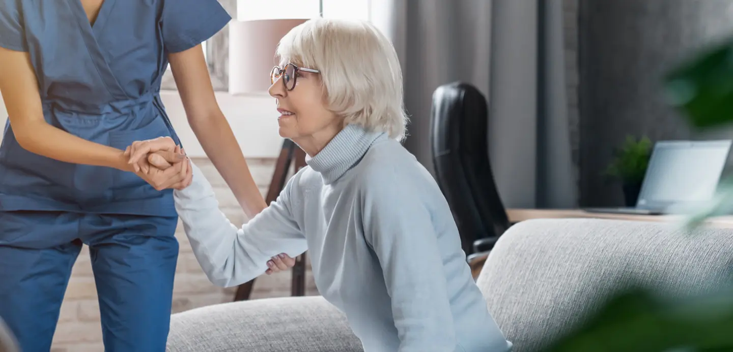 Staff assisting a senior resident in a cozy interior setting