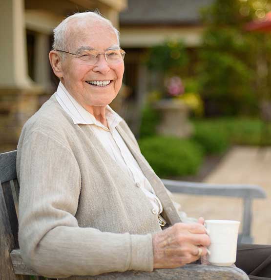 Smiling resident enjoying coffee in an outdoor setting
