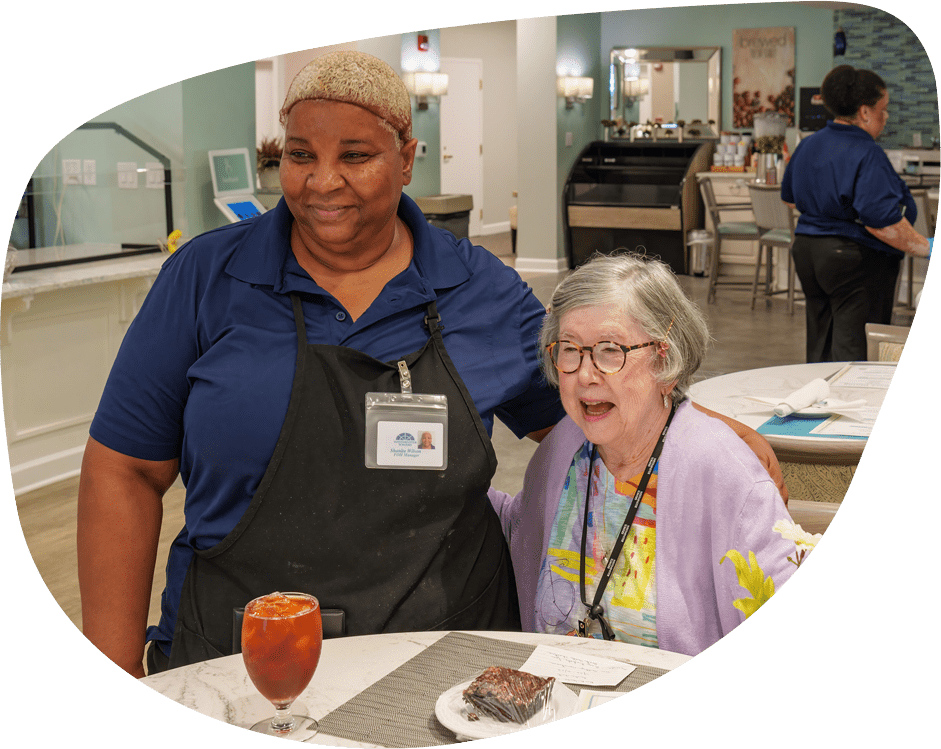 Staff member with a resident enjoying dessert in a dining area