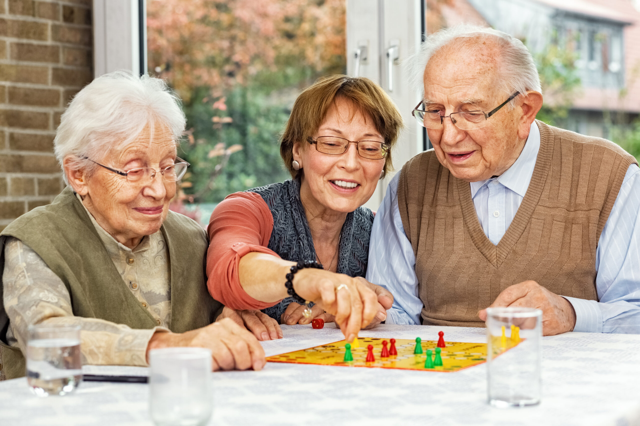 Residents and staff playing a board game at a table