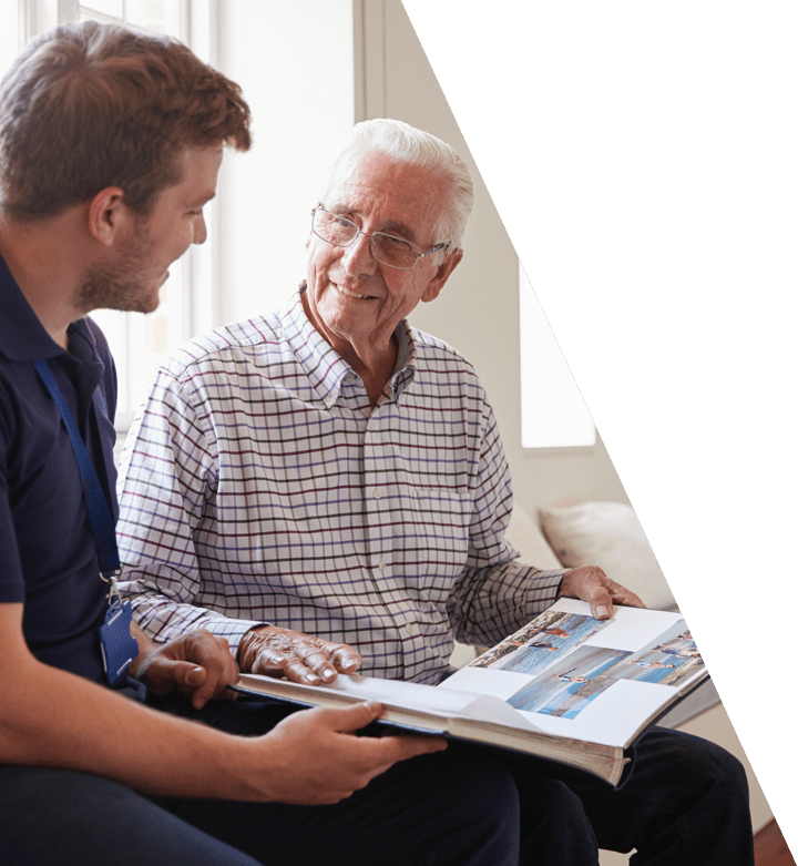 Elderly resident and staff member engaging over a photo book