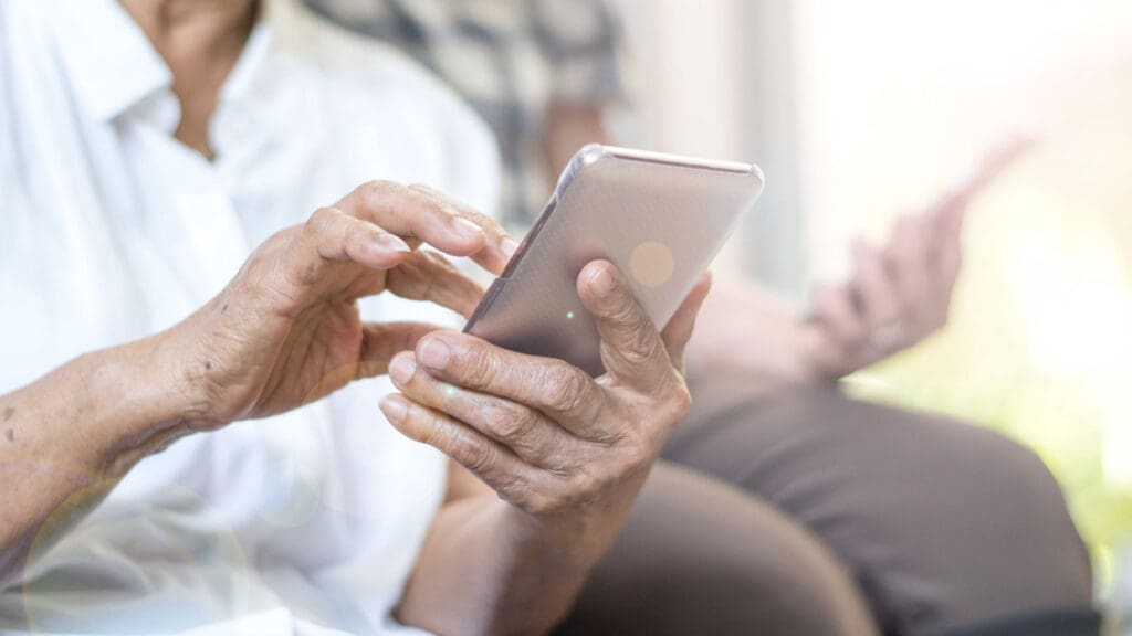 Senior resident using a smartphone in a cozy setting.