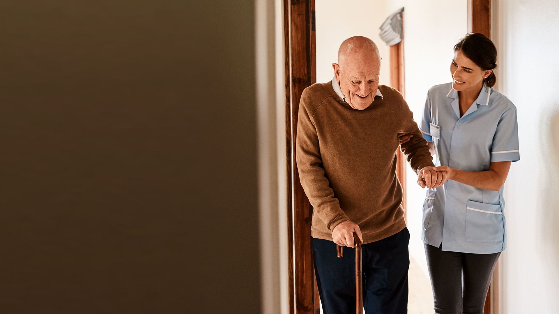 Staff member assisting a senior resident in a hallway