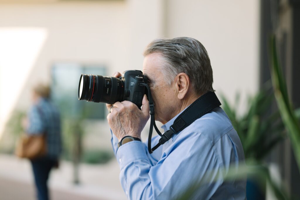 A senior man photographing outdoors with a professional camera
