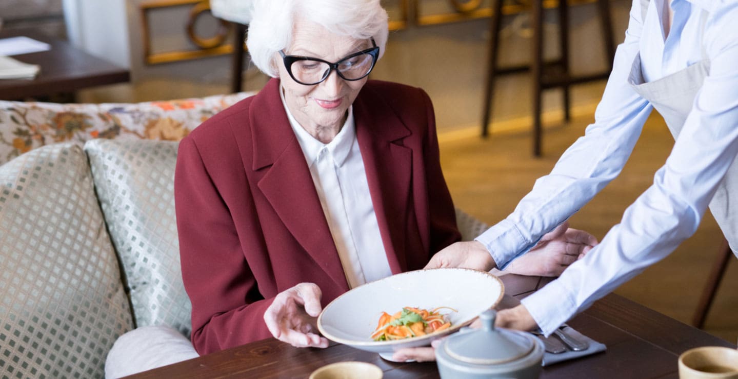 A resident receiving a plated meal in a cozy dining area