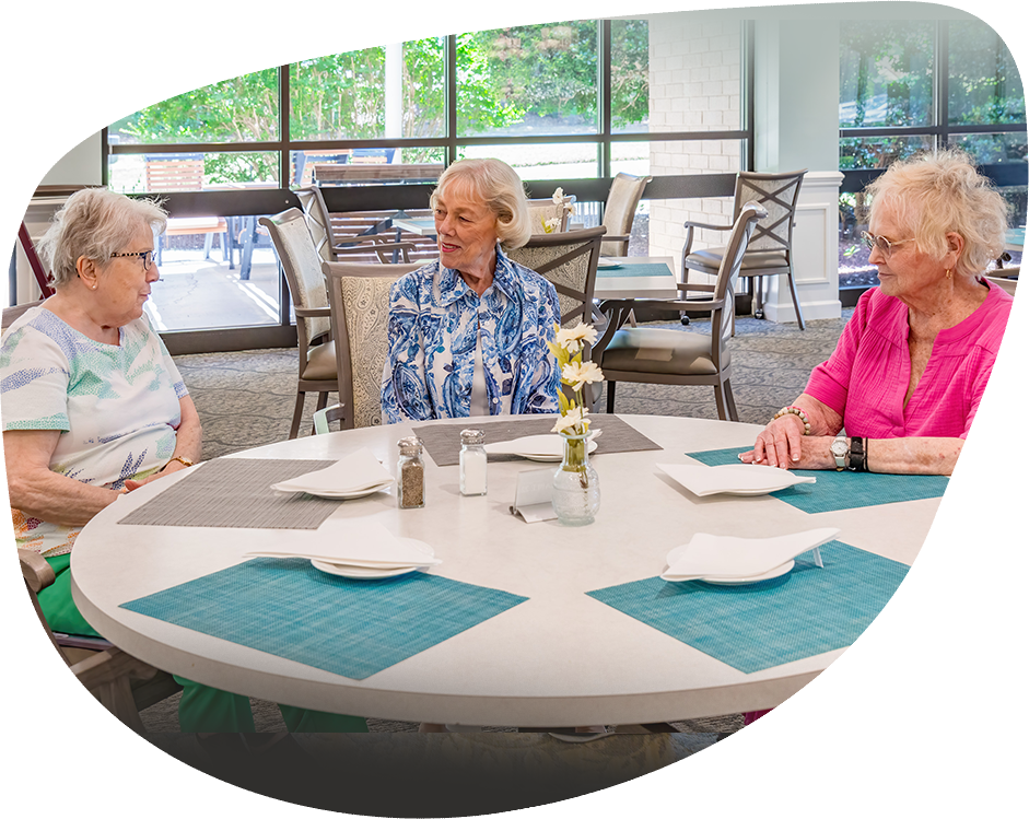 Three residents enjoying conversation in the dining room