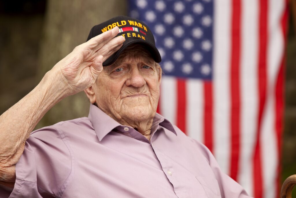 A senior veteran saluting in front of an American flag