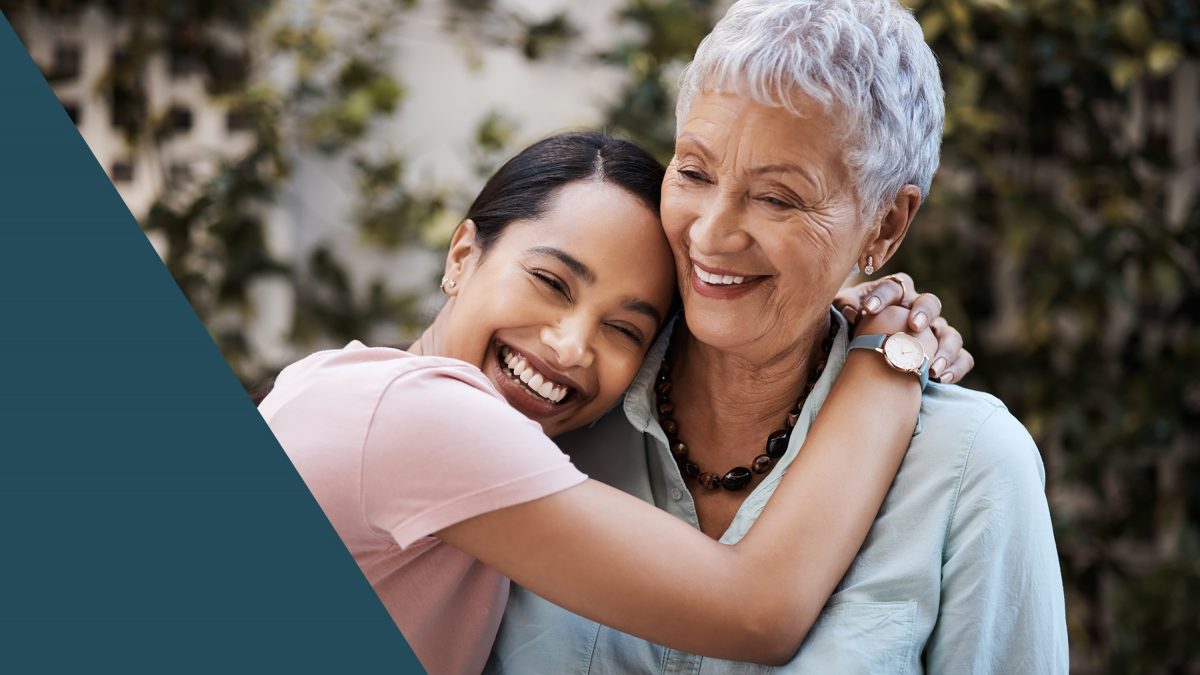 A caregiver embraces a happy resident outdoors