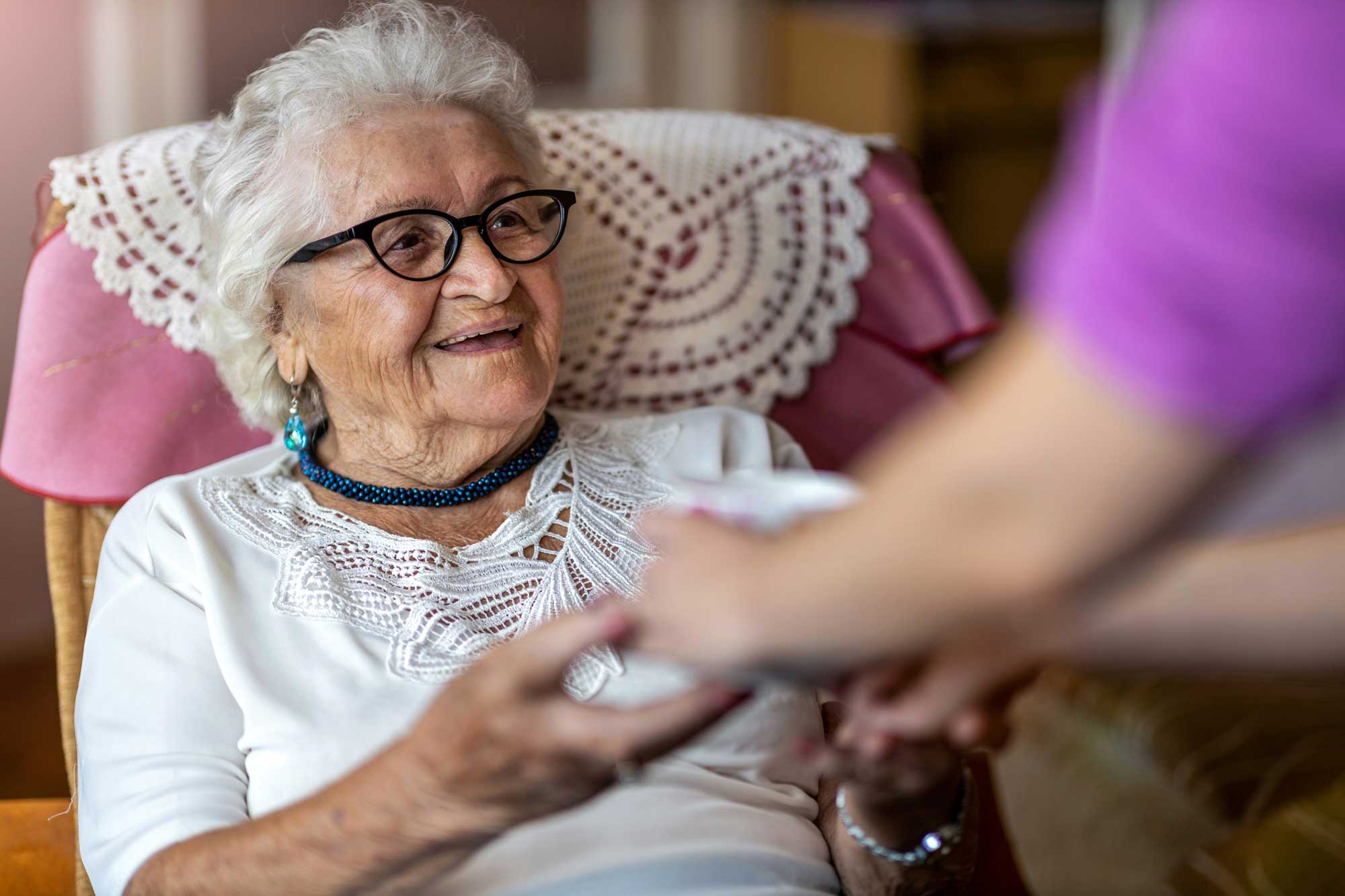 Smiling resident receiving a drink from staff