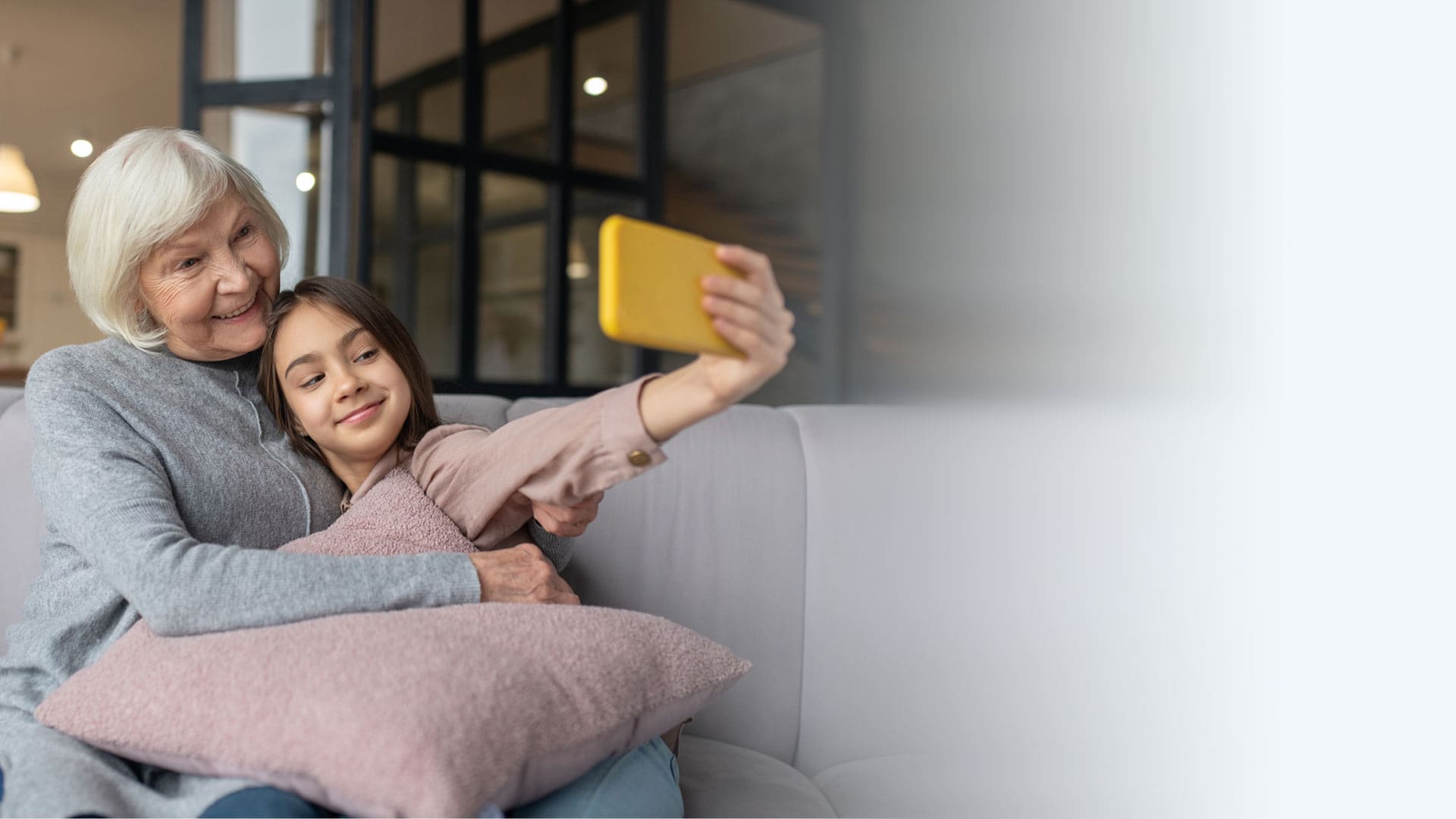 Grandmother and granddaughter taking a selfie in a cozy living room